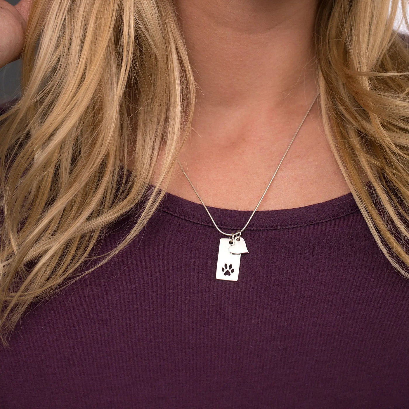 Silver dog paw tag necklace with small heart charm made of sterling silver for pet lovers