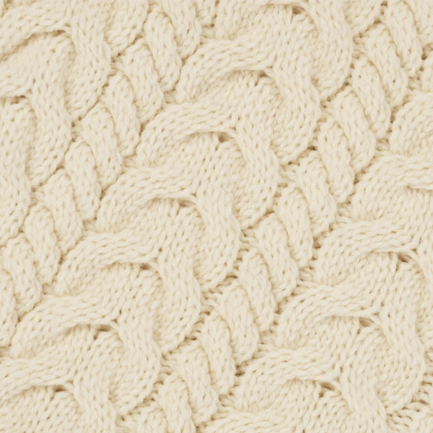 Cream-colored cable-knit irish aran wool poncho fabric with textured interwoven pattern close-up view