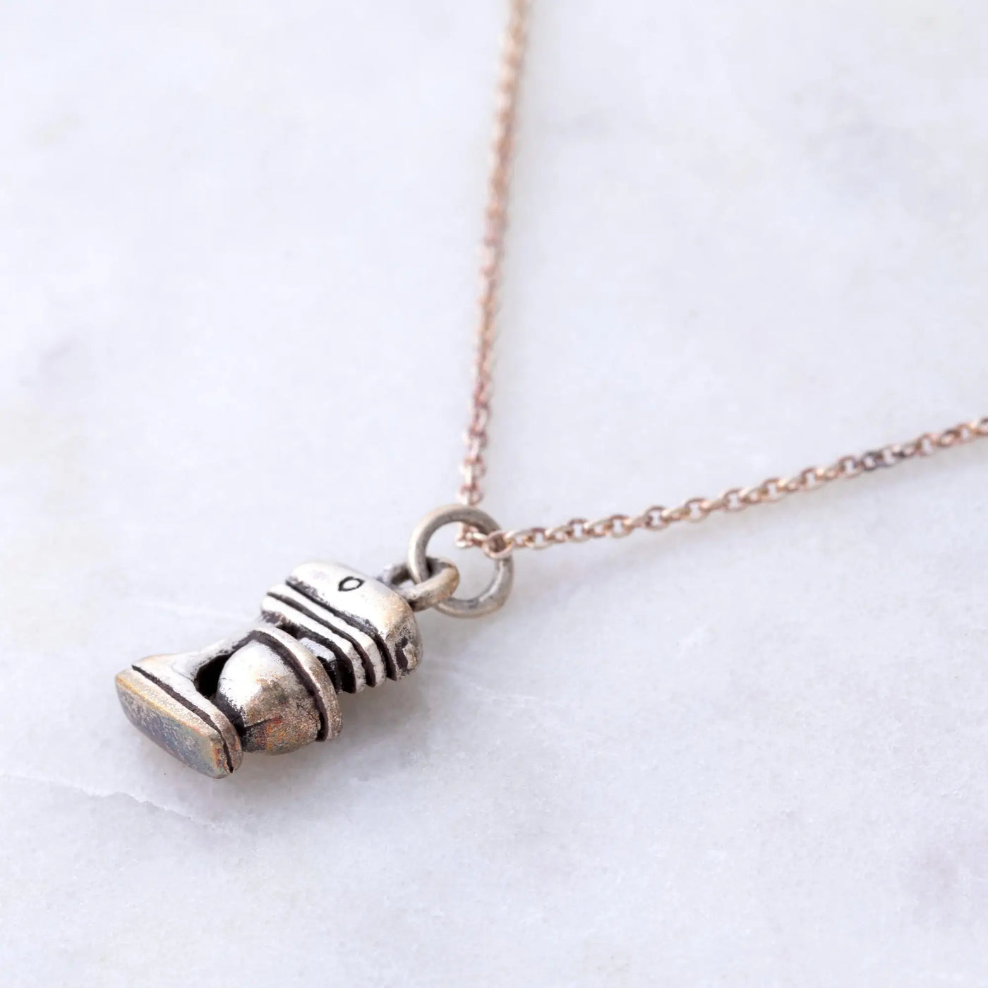 A silver-toned miniature toilet pendant with intricate details on a delicate rose gold chain sterling necklace