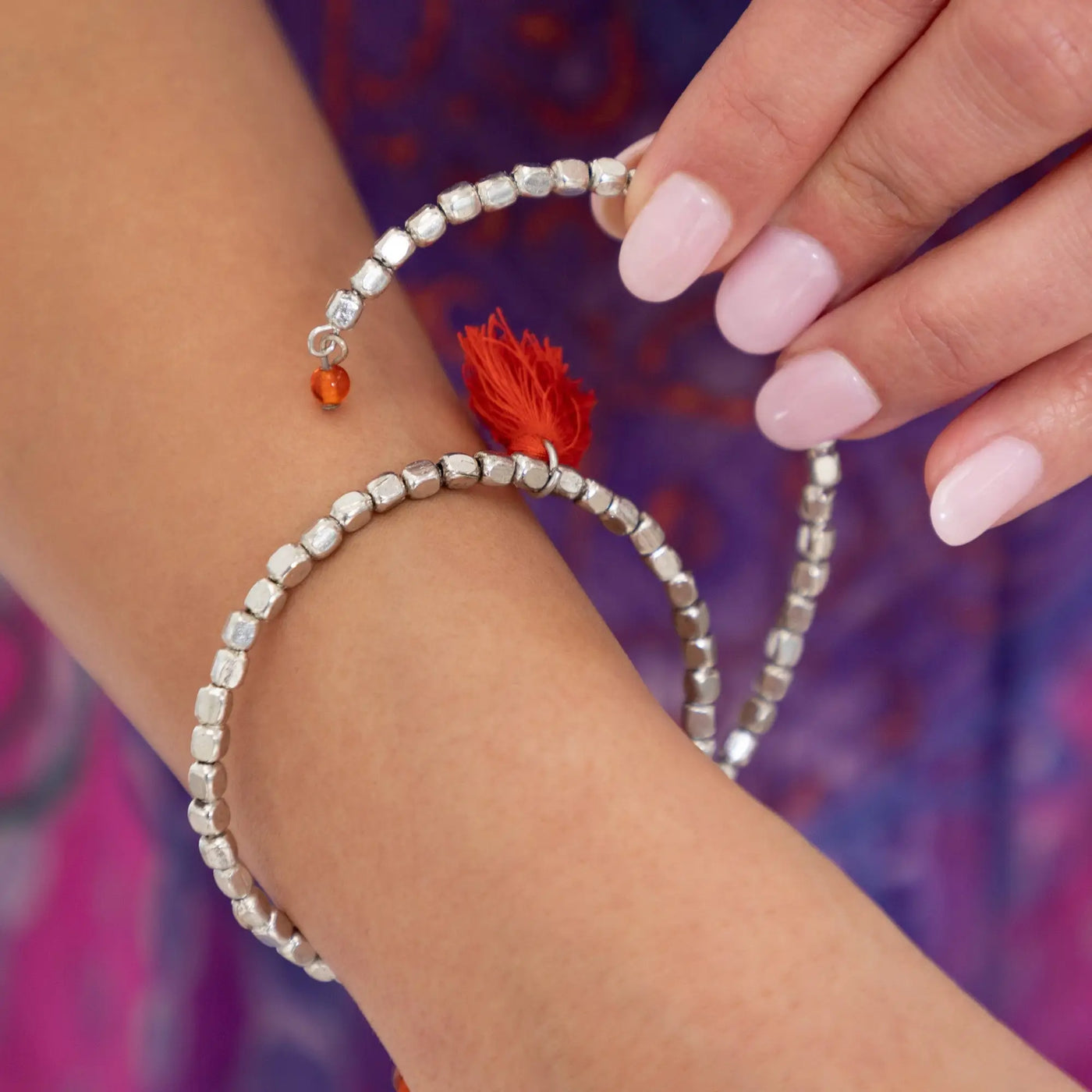 Silver beaded taj tassel metal bracelet with red tassel and orange bead accent for stylish wear