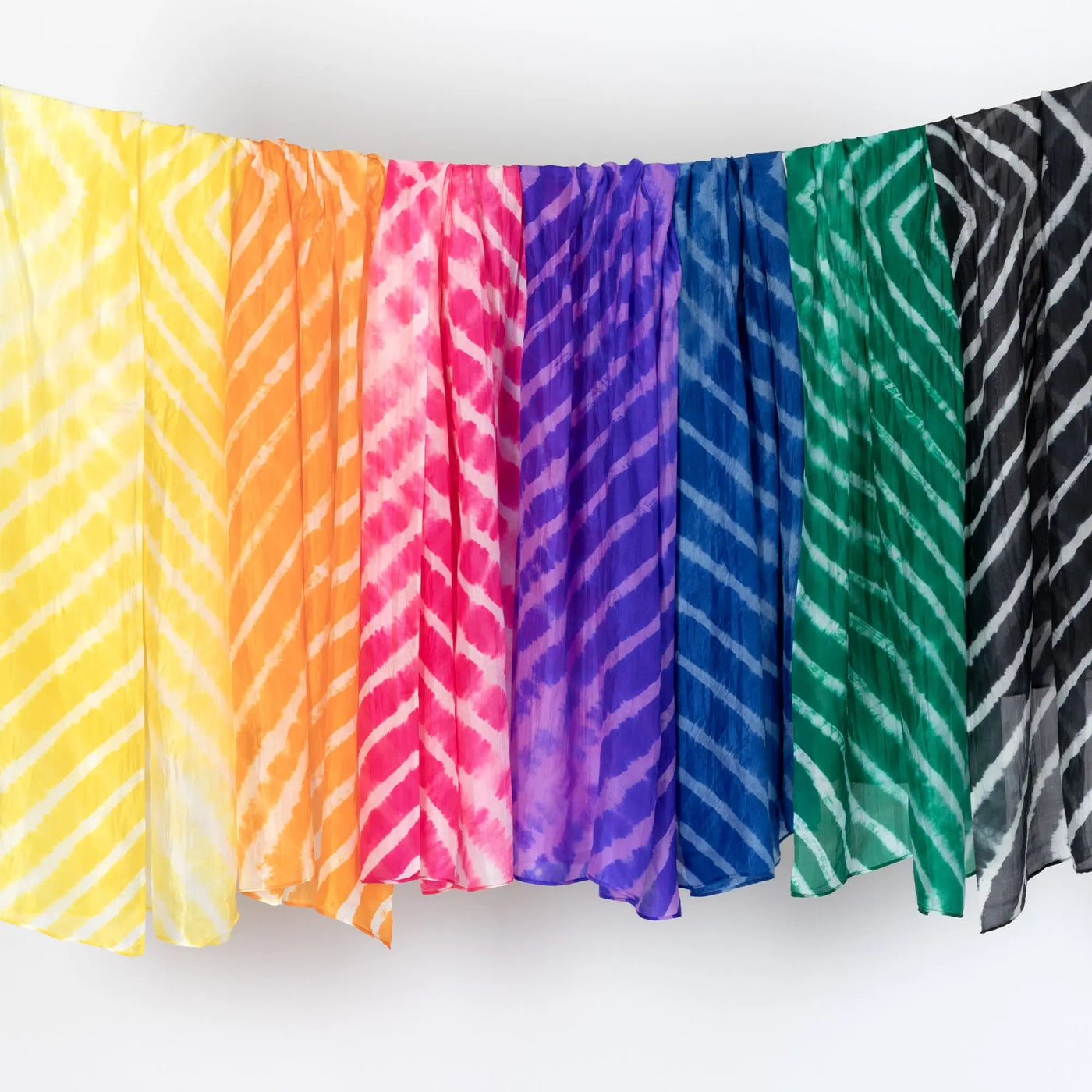 A collection of tie-dye stripe silk scarves in vibrant yellow orange pink purple blue green and black hues