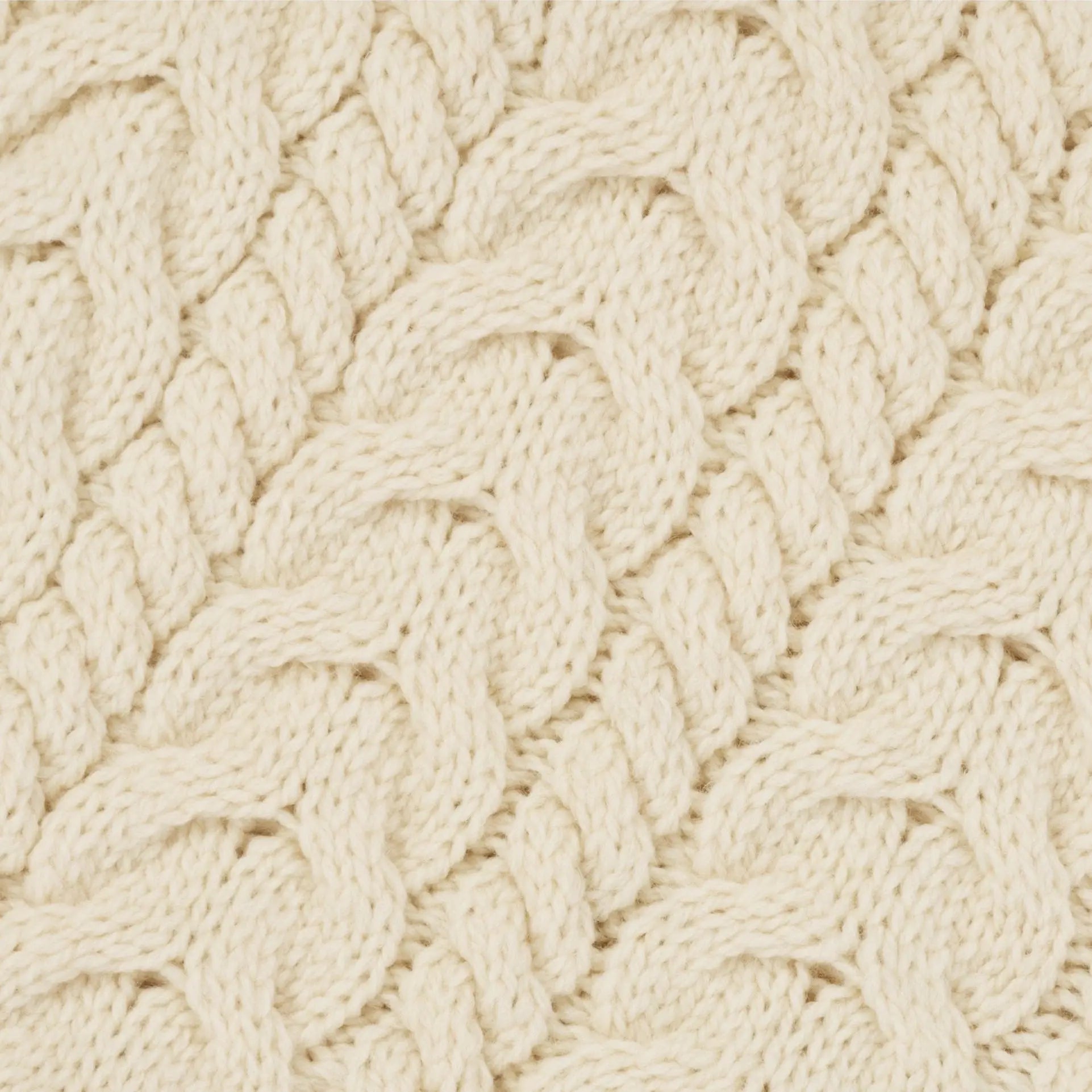 Cream-colored cable-knit irish aran wool poncho fabric with textured interwoven pattern close-up view