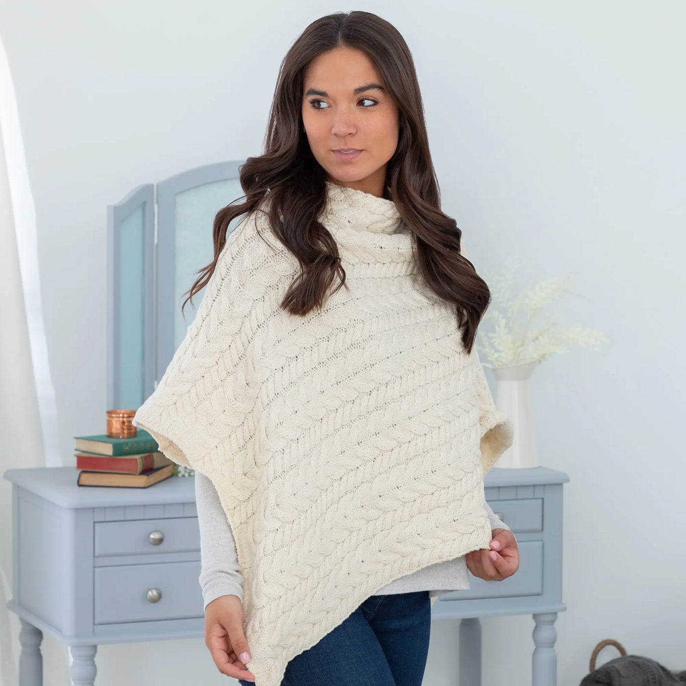 Cream-colored Irish aran wool poncho with cable knit and high turtleneck collar for cozy warmth