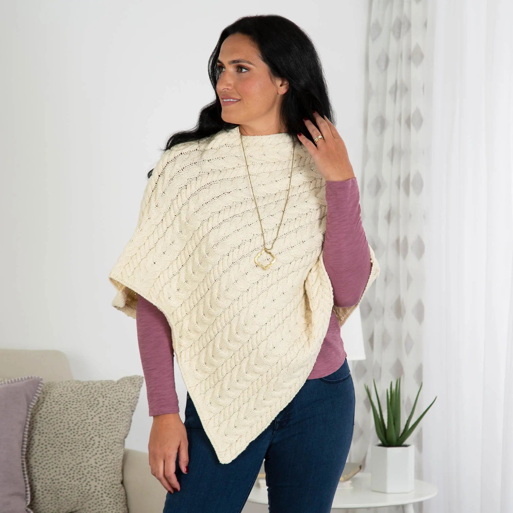 Cream-colored Irish Aran wool poncho with hand-knitted cable knit pattern and soft cozy textured fabric