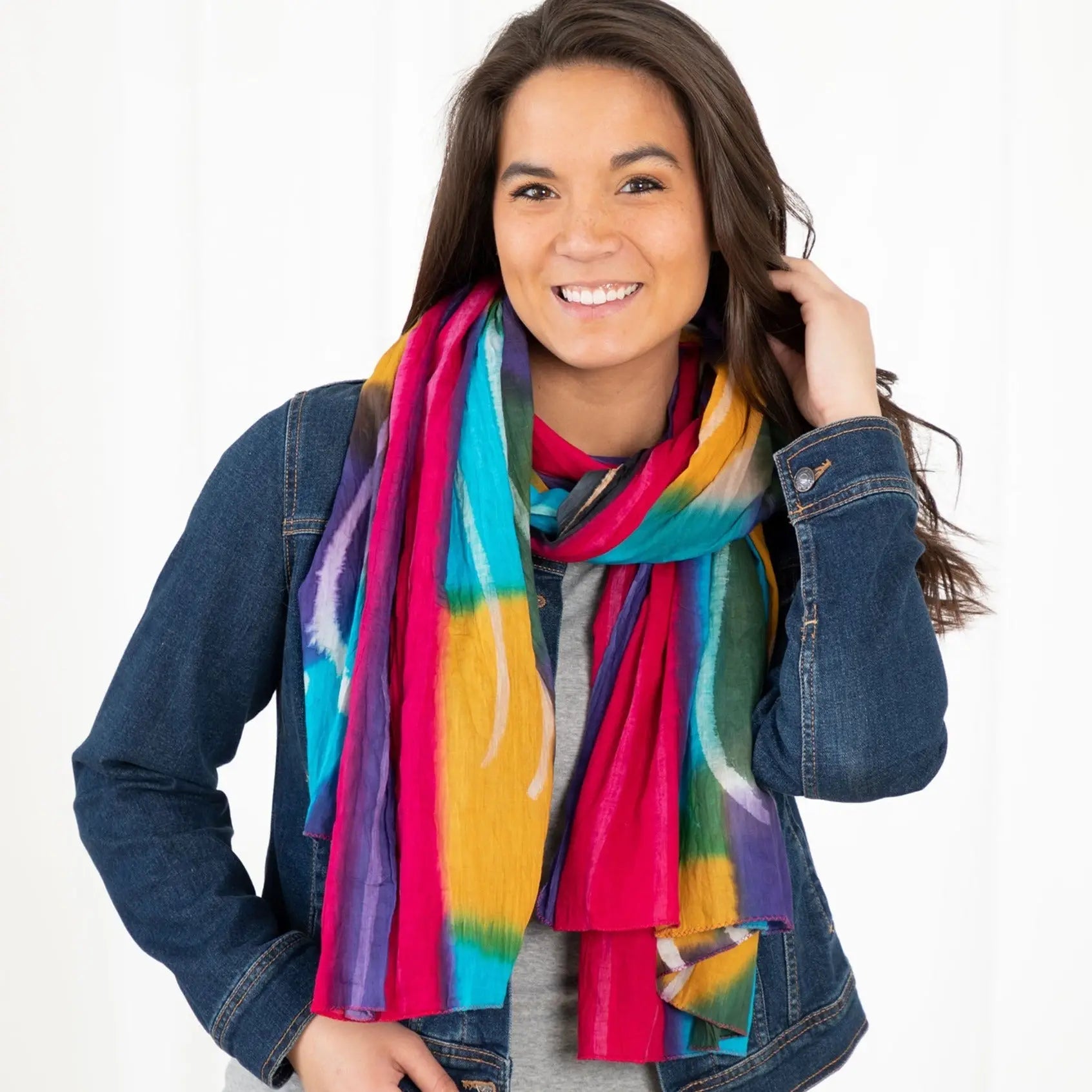 Northern lights cotton scarf fair trade with vibrant multicolored tie dye stripes in pink teal yellow and purple draped around neck