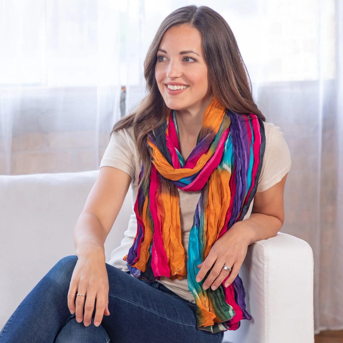 A vibrant multicolored striped northern lights cotton scarf drapes softly around the model’s neck fair trade made