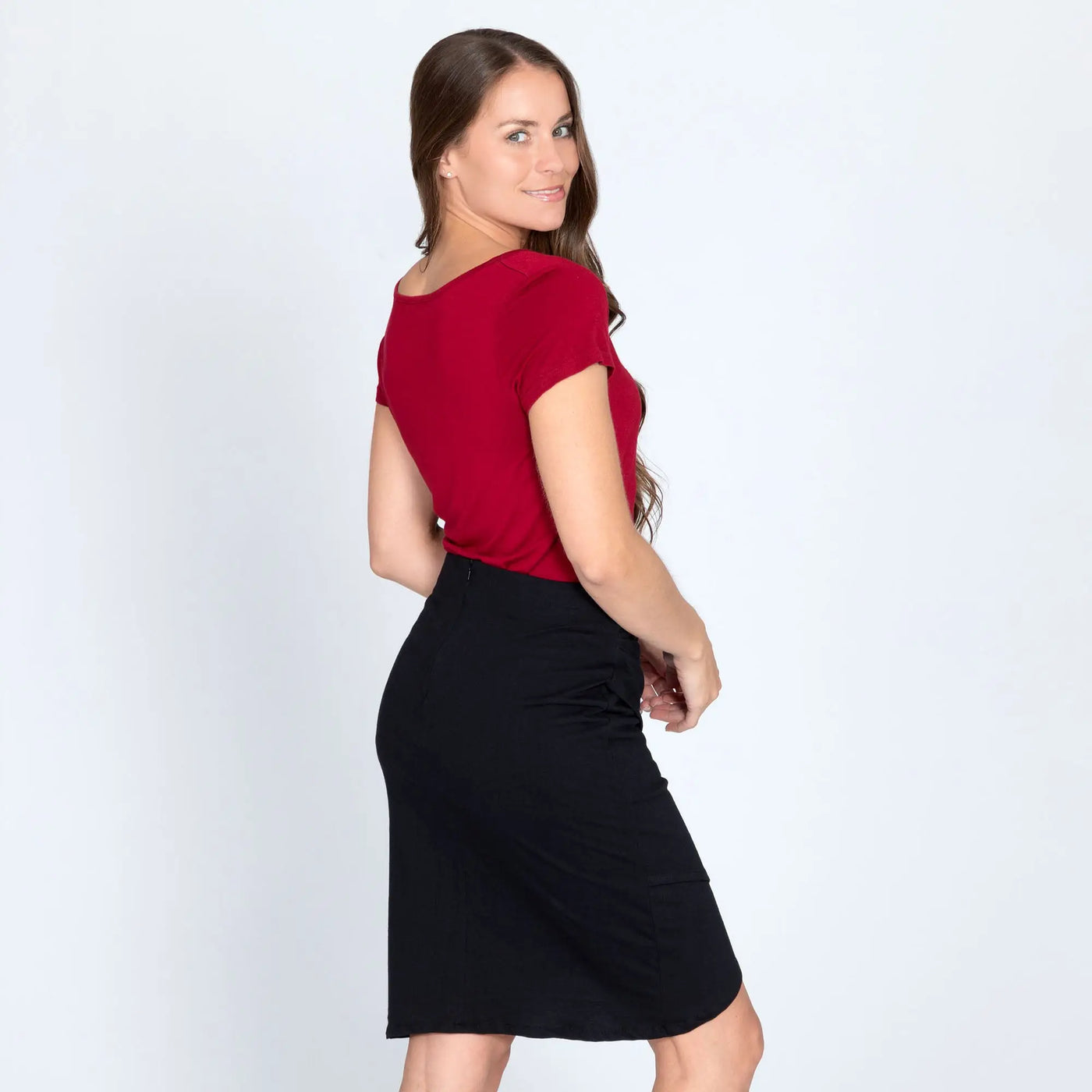 A woman wears an organic layered black pencil skirt paired with a vibrant red short-sleeved top