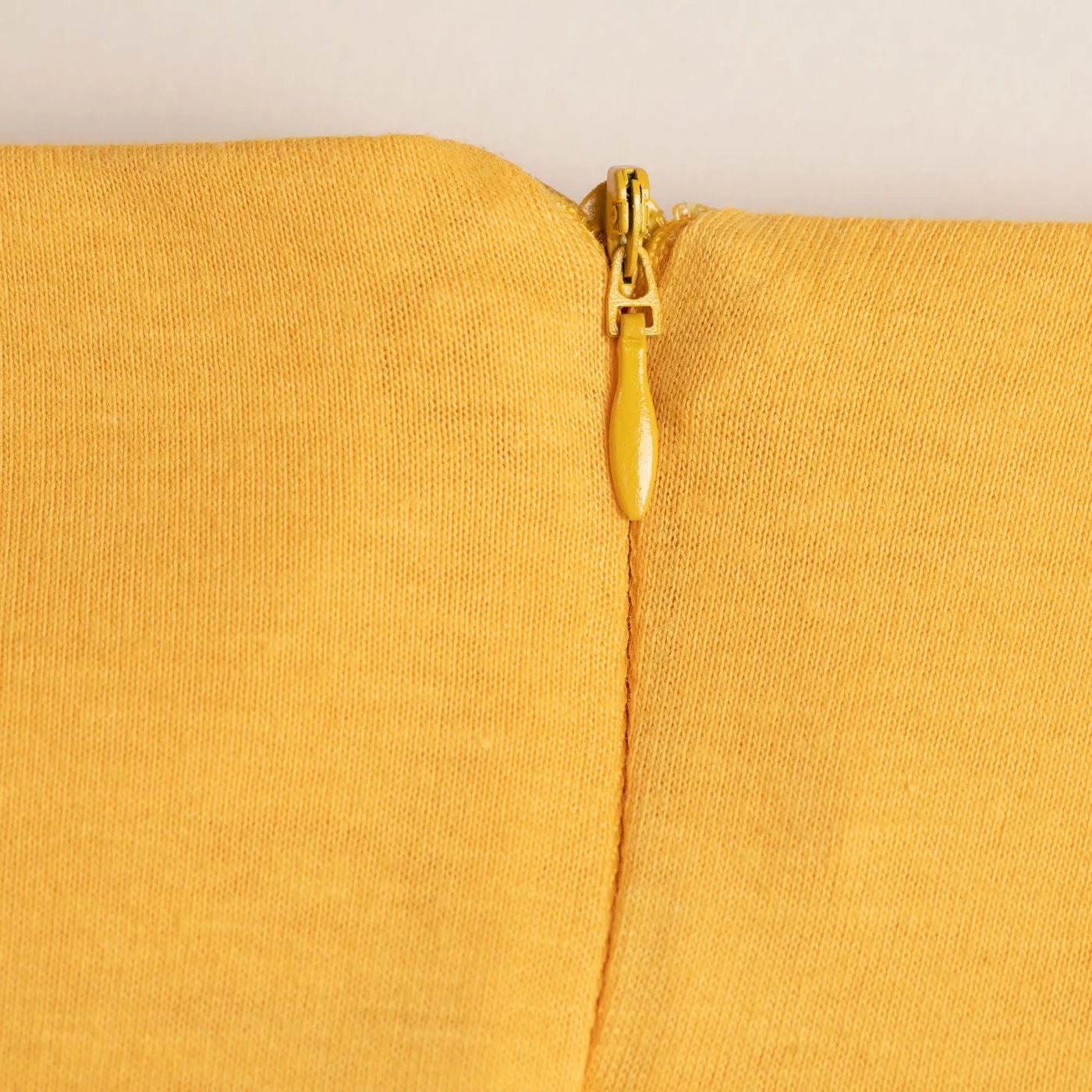 Organic layered pencil skirt featuring a yellow zipper with matching pull tab on textured mustard fabric