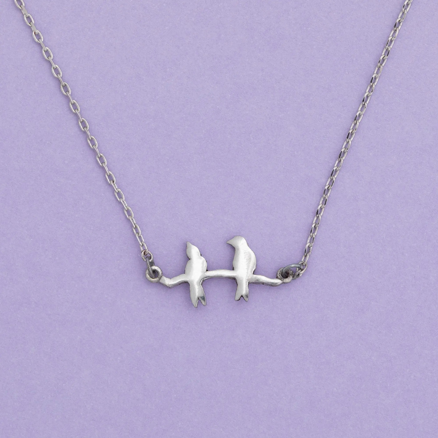 Silver sisterly love necklace featuring two birds perched on a branch with delicate metalwork design