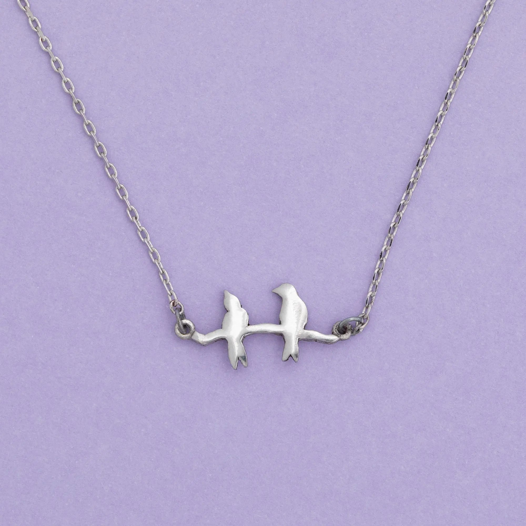Silver sisterly love necklace featuring two birds perched on a branch with delicate metalwork design