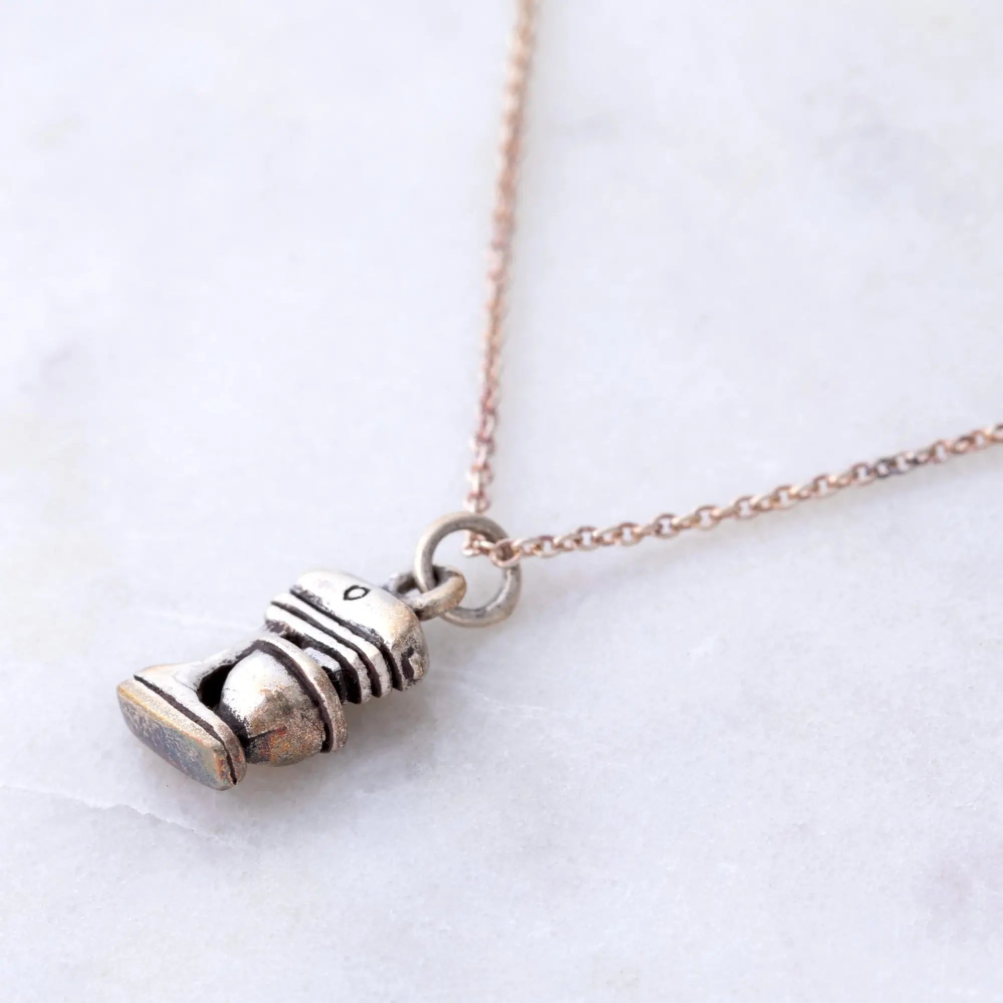 A silver-toned miniature toilet pendant with intricate details on a delicate rose gold chain sterling necklace