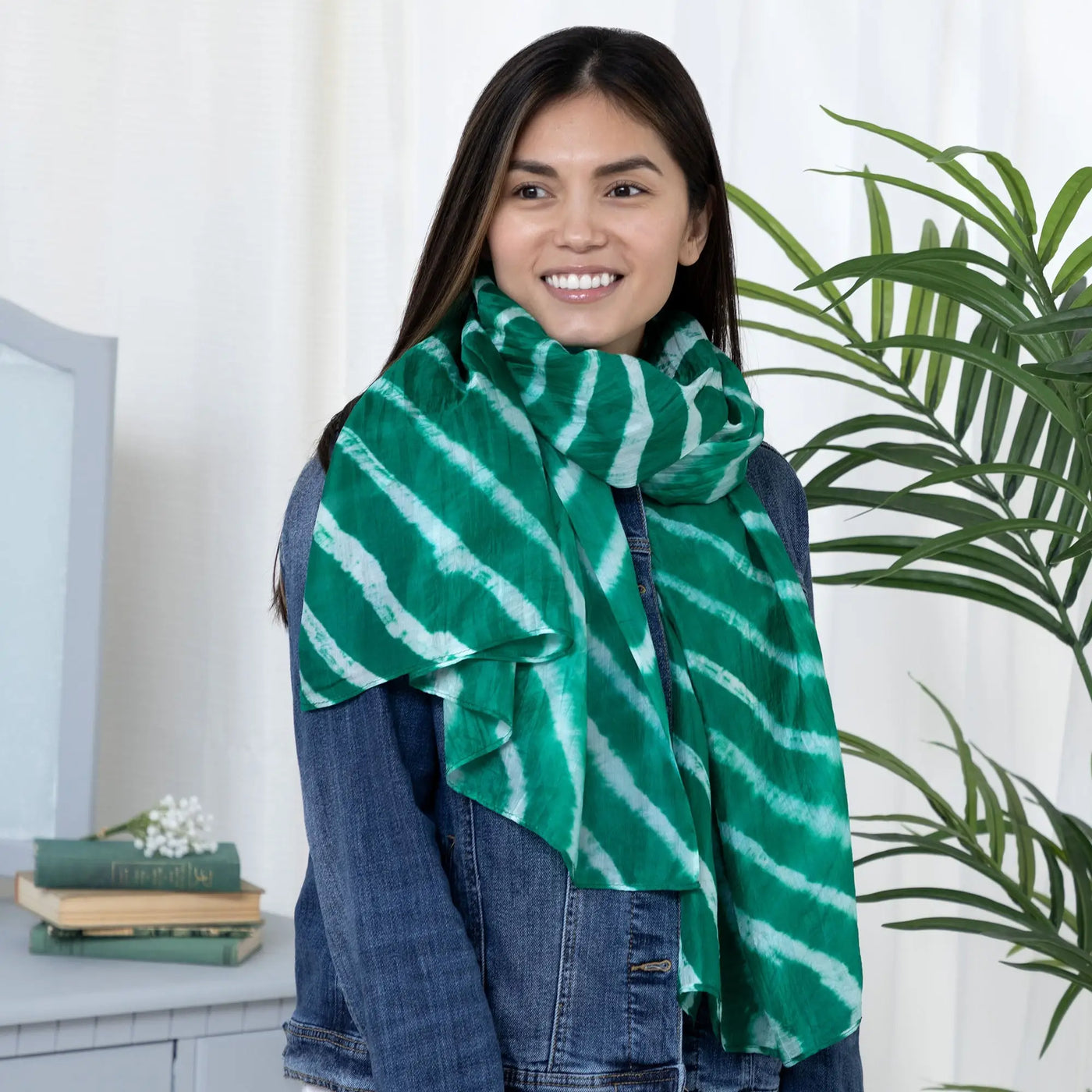 A vibrant green and white tie-dye stripe silk scarf with lightweight fabric draped around the model’s neck