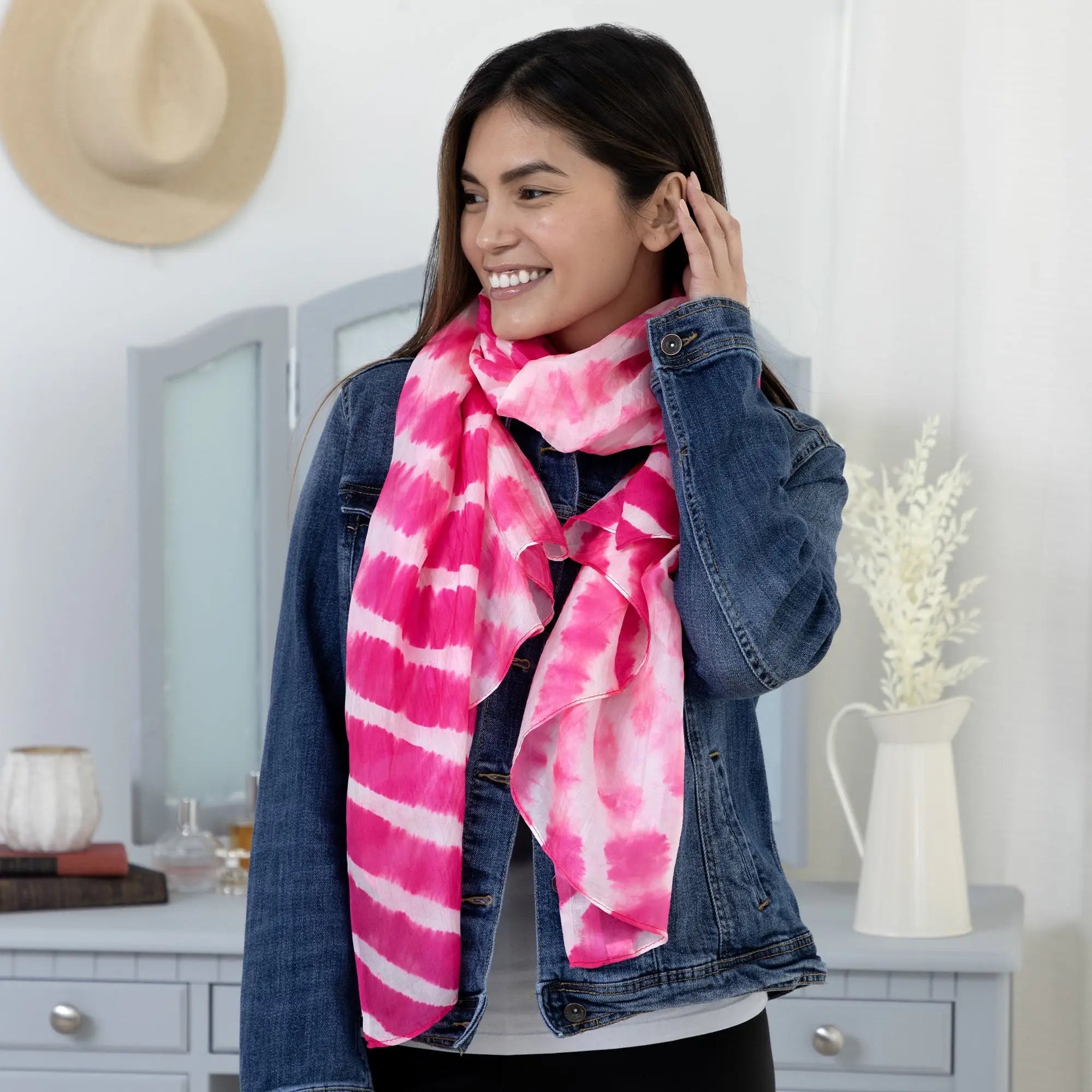 A vibrant pink and white tie-dye stripe silk scarf with lightweight fabric draped elegantly around the neck