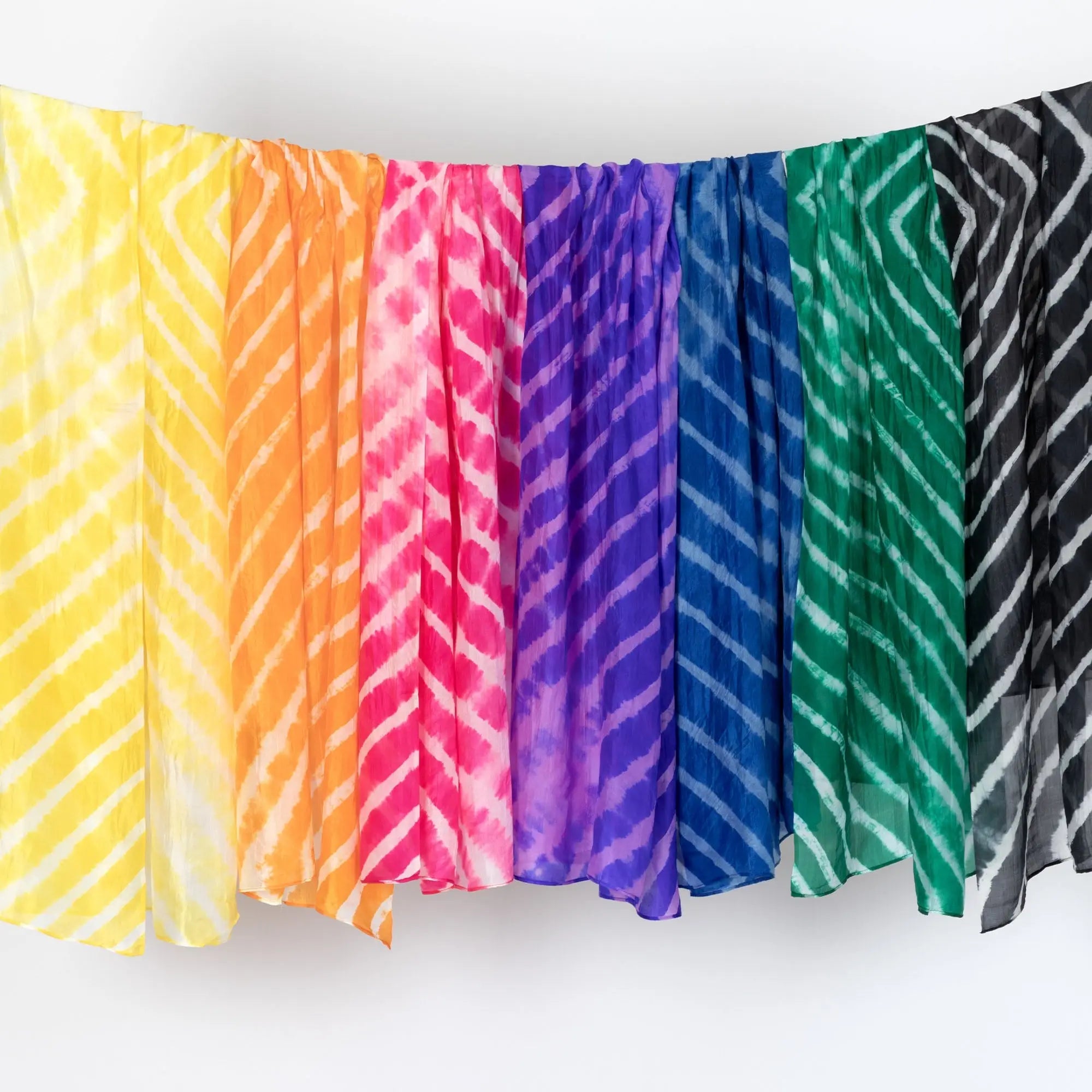 A collection of tie-dye stripe silk scarves in vibrant yellow orange pink purple blue green and black hues