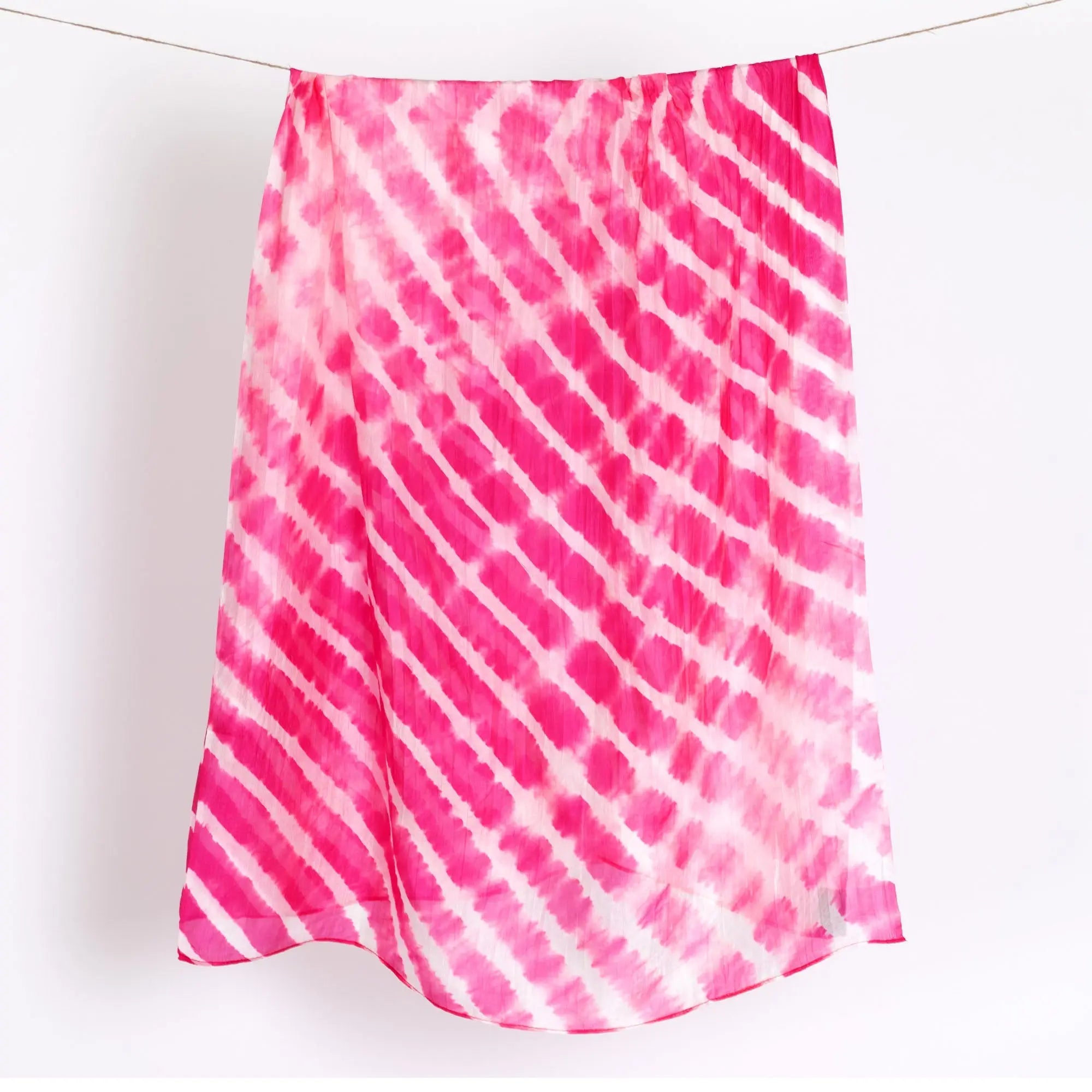 A flowing pink and white tie-dye silk scarf with diagonal stripes perfect for stylish accessorizing